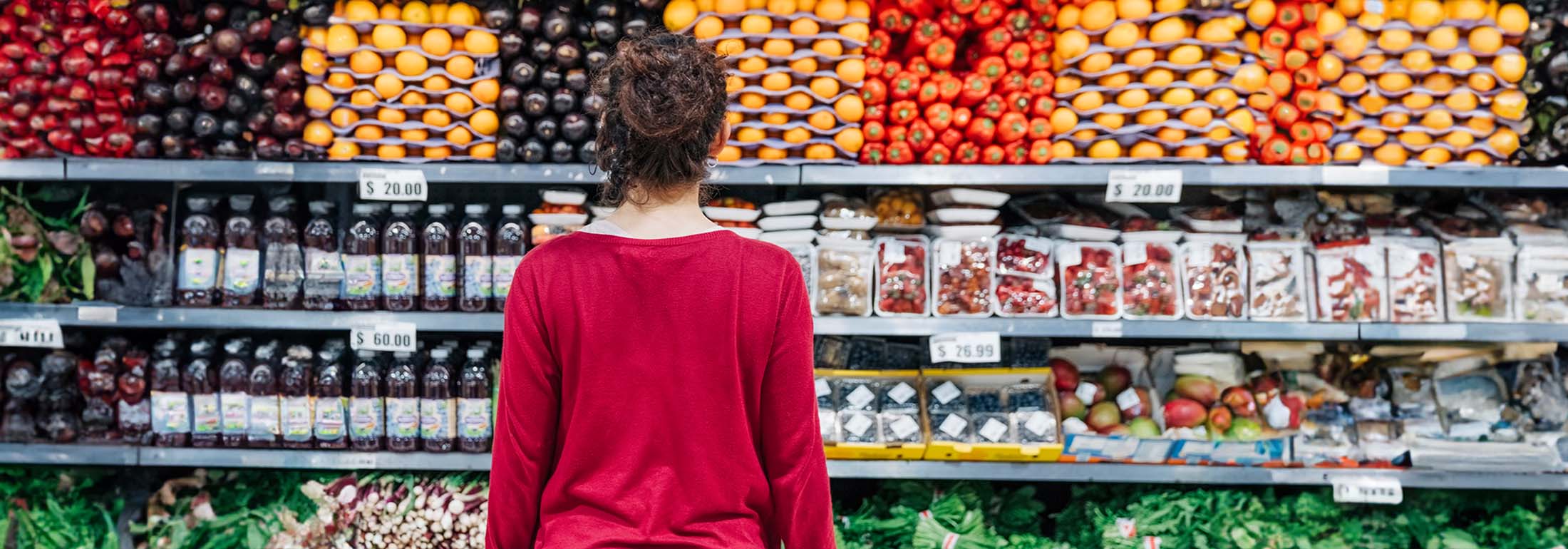 Frau beim Einkaufen vor Obst und Gemüseregal